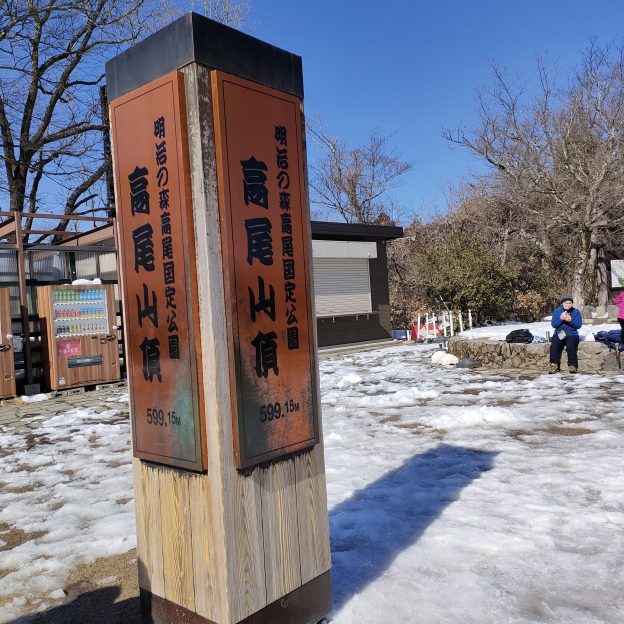 残雪の高尾山山頂標識と青空